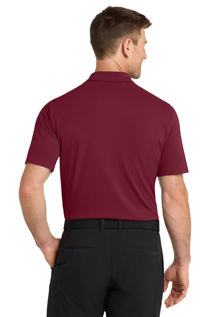 Man wearing a maroon polo shirt and black pants on a white background. Nike Dri-FIT Micro Pique 2.0 Polo, Embroidered by Helmsman Stitch Co.