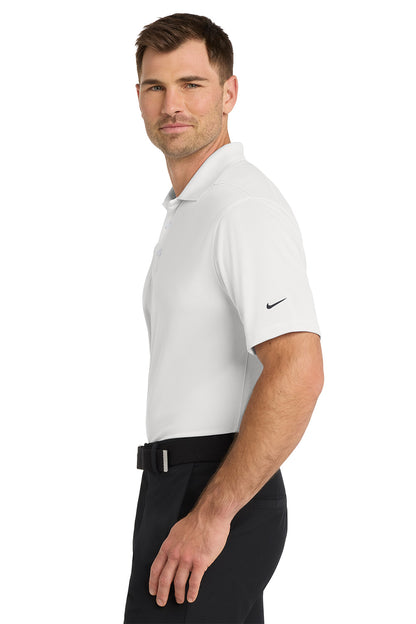 Man wearing a white Nike polo shirt and black pants on a white background. Nike Dri-FIT Micro Pique 2.0 Polo, Embroidered by Helmsman Stitch Co.