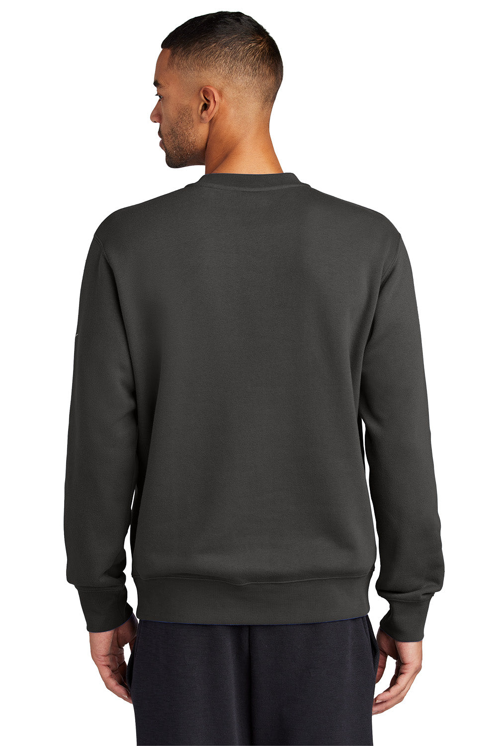 Person wearing a dark gray sweatshirt on a white background embroidered Nike Club Fleece Sleeve Swoosh Crew