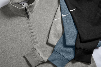 Three Nike quarter-zip pullover sweatshirts arranged diagonally, showing gray, heather blue, and black colorways with white embroidered swoosh logos. Nike Dri-FIT Corporate 1/2-Zip, Embroidered