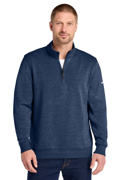 A man wearing a navy blue heathered quarter-zip pullover sweatshirt with a small white Nike swoosh on the left sleeve, paired with dark blue jeans, against a plain white background. Nike Dri-FIT Corporate 1/2-Zip, Embroidered