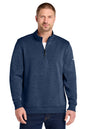 A man wearing a navy blue heathered quarter-zip pullover sweatshirt with a small white Nike swoosh on the left sleeve, paired with dark blue jeans, against a plain white background. Nike Dri-FIT Corporate 1/2-Zip, Embroidered