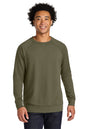 A man wearing an olive green long-sleeve crewneck sweatshirt, paired with dark blue jeans, standing against a plain white background. Next Level Apparel® Laguna Raglan Sweatshirt, Embroidered