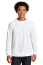 A smiling man with curly black hair wearing a plain white long-sleeve crewneck sweatshirt and dark blue jeans, standing against a solid white background. Next Level Apparel® Laguna Raglan Sweatshirt, Embroidered