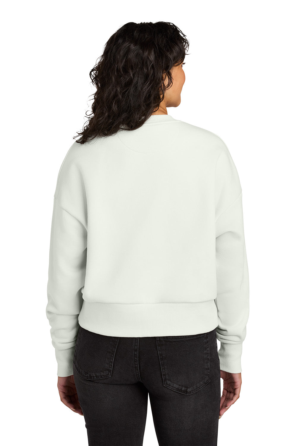 Person wearing a light gray sweatshirt and dark jeans on a white background. Next Level Apparel® Women’s Heavyweight Sweatshirt, Embroidered