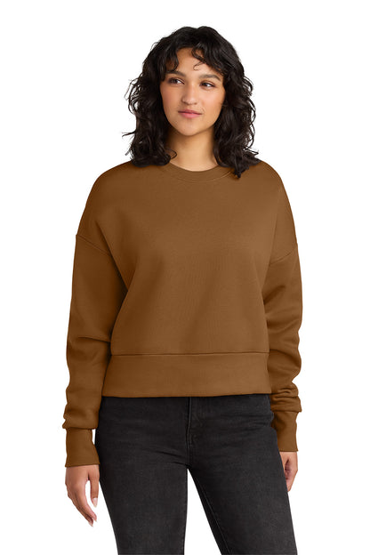 Woman wearing a brown sweatshirt and black pants on a white background. Next Level Apparel® Women’s Heavyweight Sweatshirt, Embroidered