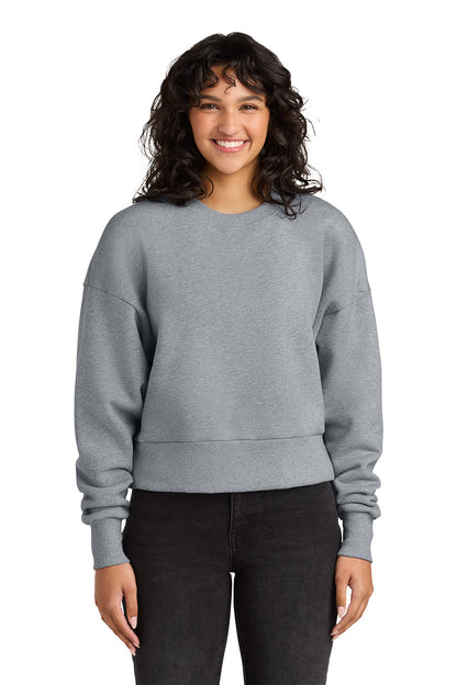 Person wearing a gray sweatshirt and black pants on a white background. Next Level Apparel® Women’s Heavyweight Sweatshirt, Embroidered