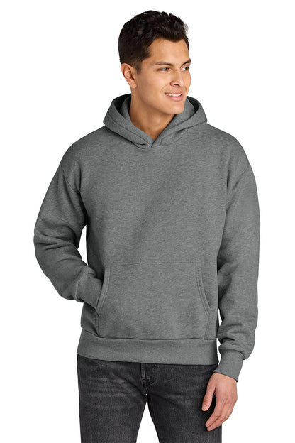 A man wearing a heather gray pullover hoodie with a front kangaroo pocket, paired with dark gray jeans, shown against a plain white background. Next Level Apparel® Heavyweight Hoodie, Embroidered