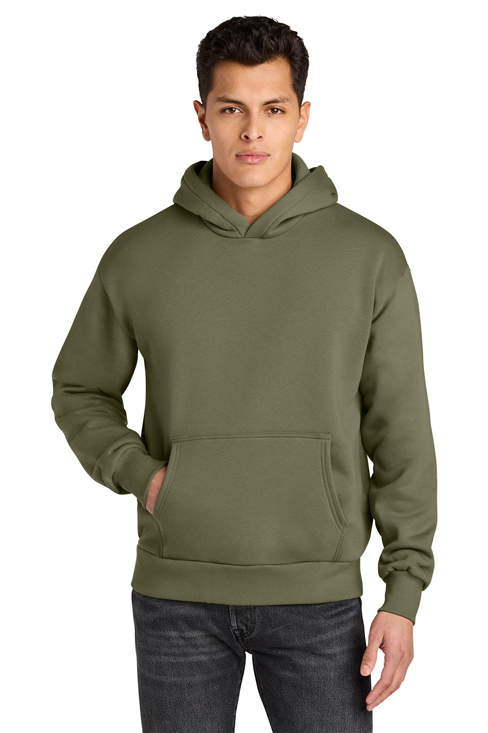 A man wearing an olive green pullover hoodie with a kangaroo pocket, paired with dark gray jeans, against a plain white background. Next Level Apparel® Heavyweight Hoodie, Embroidered