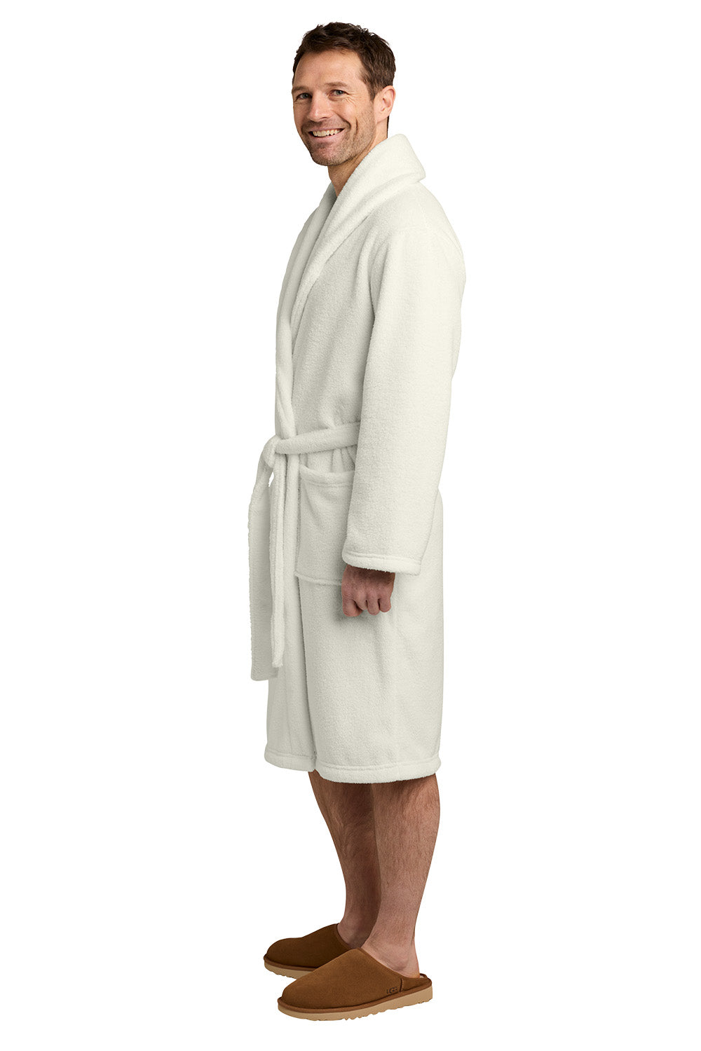 A man wearing a cream-colored plush bathrobe and brown slippers, standing in profile against a solid white background. Port Authority® Dream Plush Robe, Embroidered