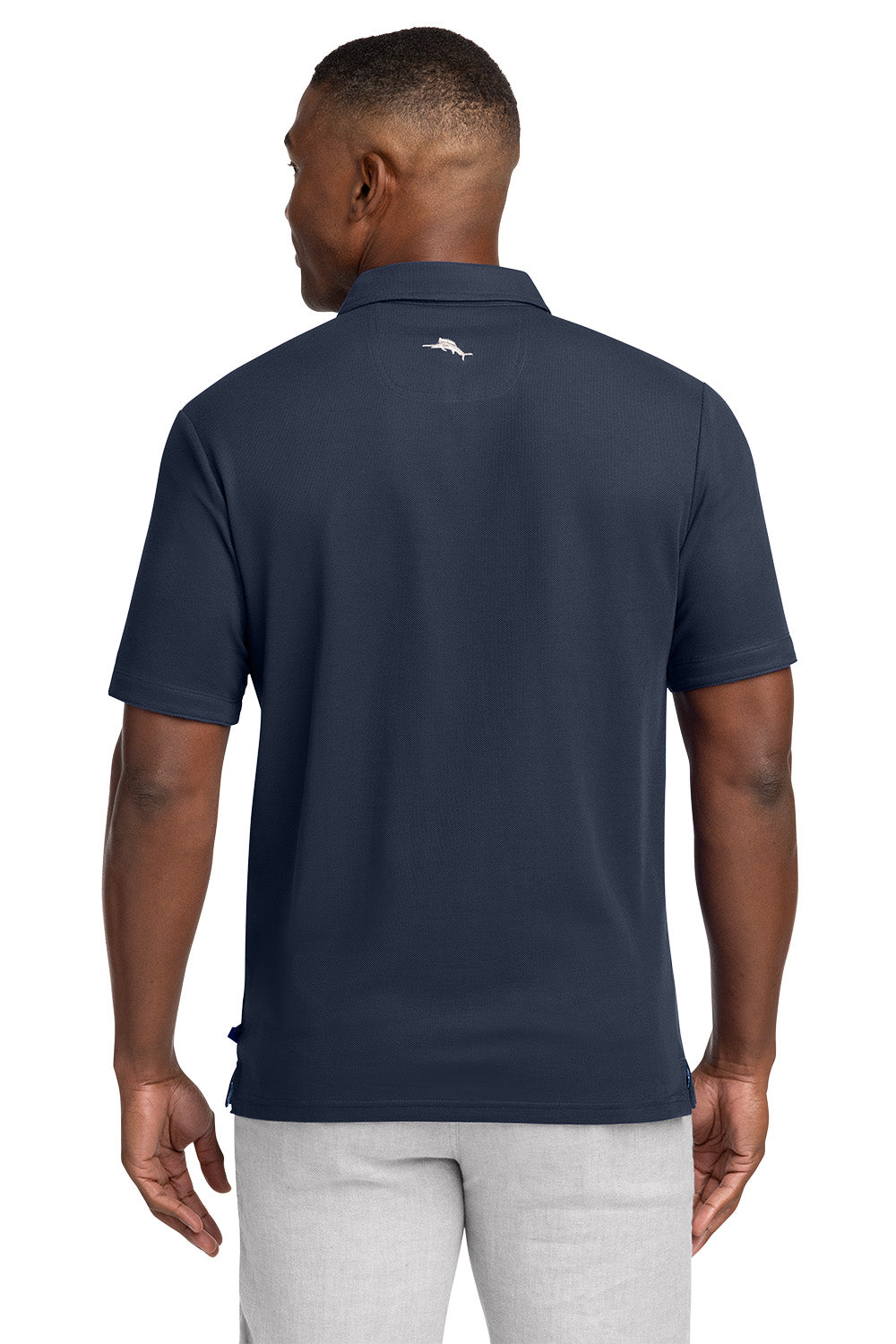 Man wearing a navy blue polo shirt with a logo on the back, standing against a white background Tommy Bahama® 5 O’Clock Polo, Embroidered
