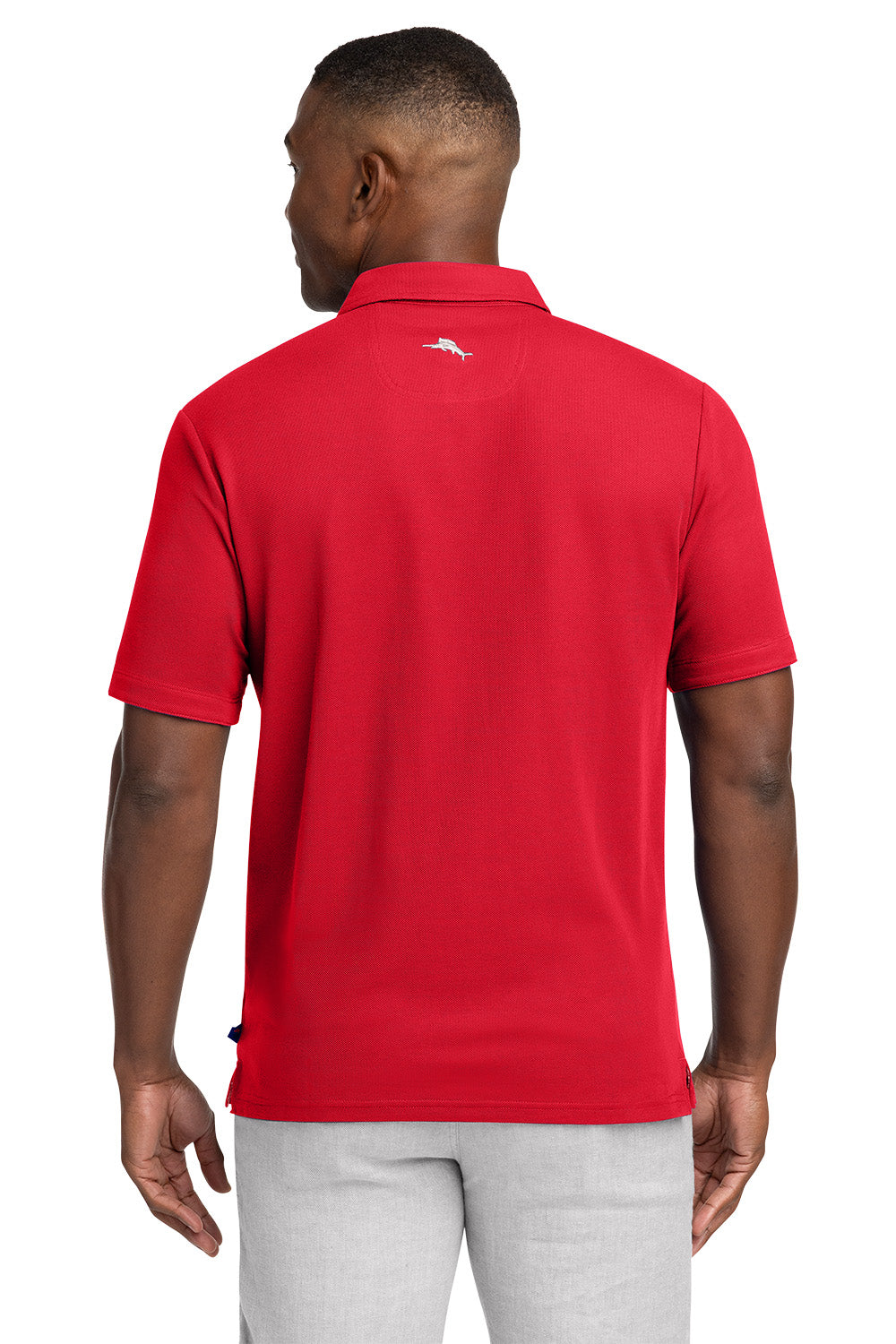 Man wearing a red polo shirt with a logo on the back, standing against a white background Tommy Bahama® 5 O’Clock Polo, Embroidered