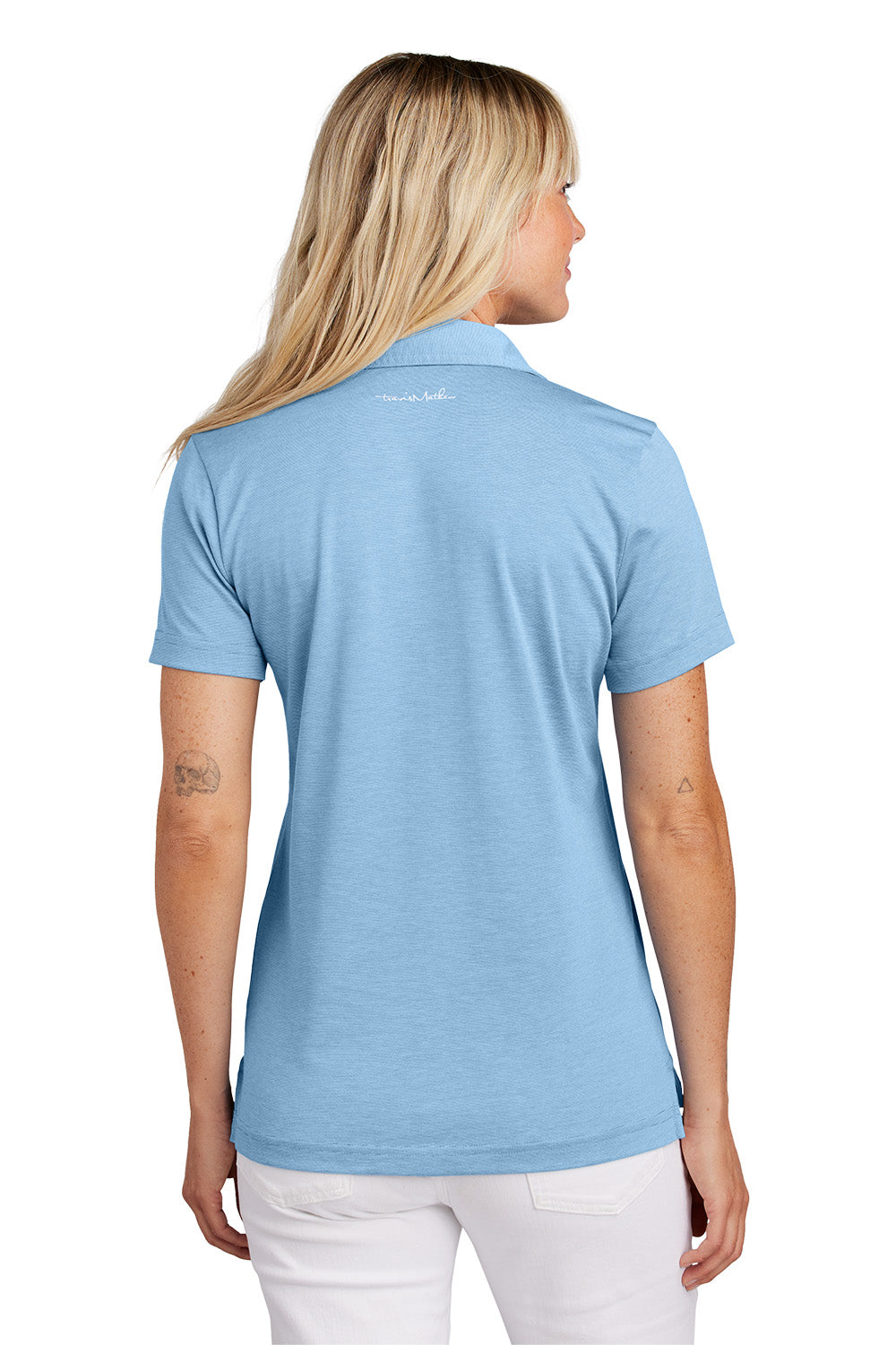 Woman wearing a light blue polo shirt with a visible brand logo on the back. Embroidered TravisMathew Women's Sunnyvale Polo