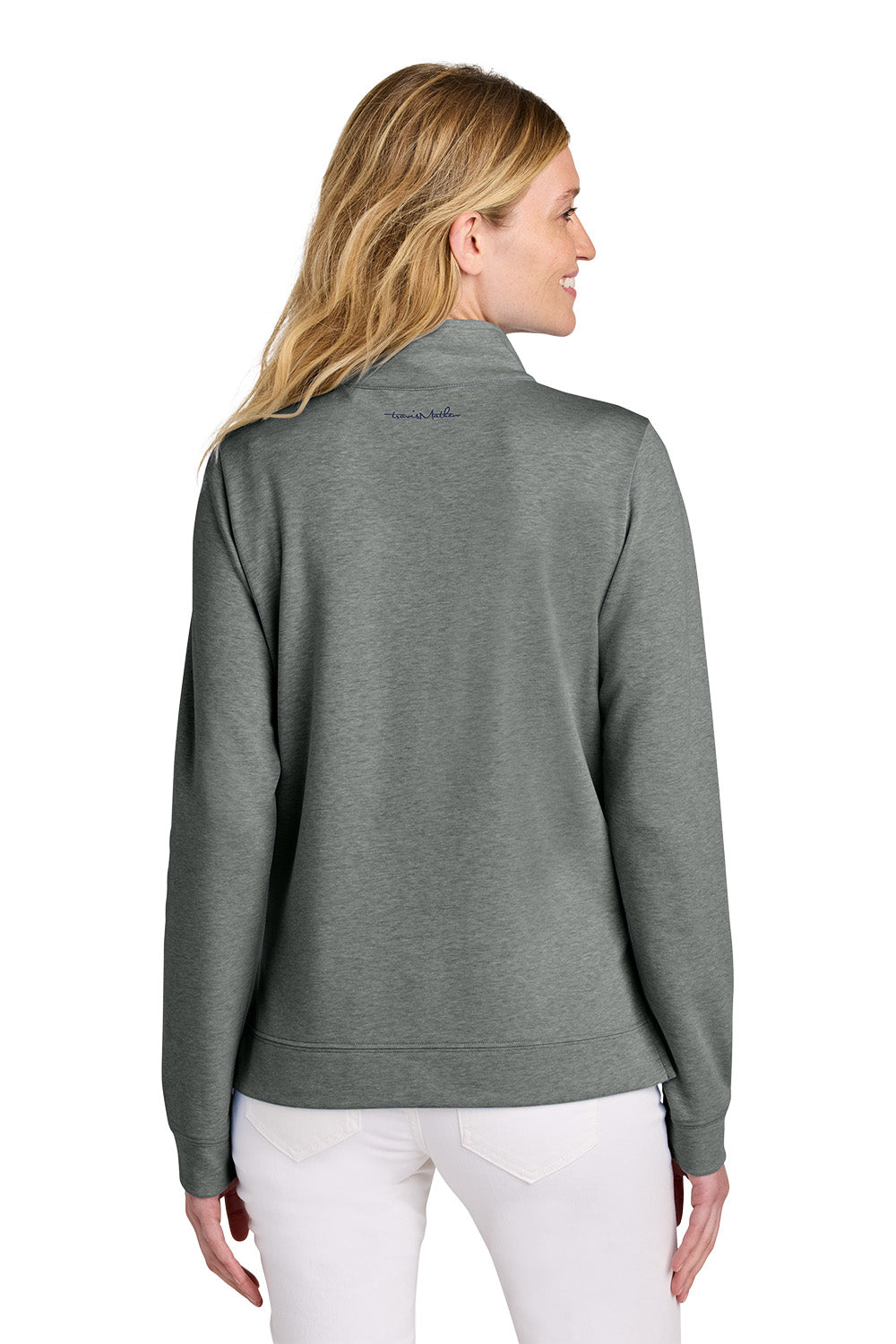 Woman wearing a gray fleece jacket with a brand logo on the back, standing against a white background. TravisMathew Women's Coveside 1/2-Zip, Embroidered