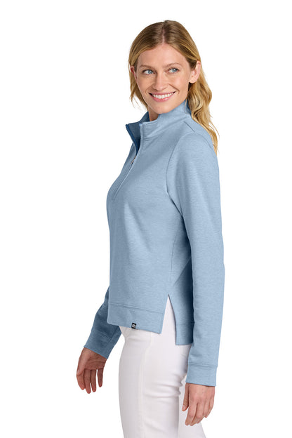 Woman wearing a light blue jacket on a white background TravisMathew Women's Coveside 1/2-Zip, Embroidered