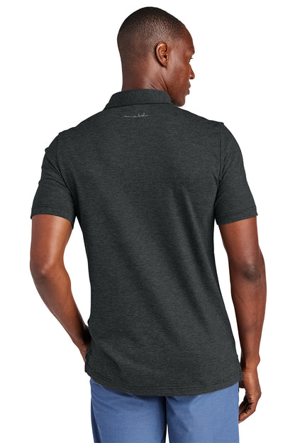 Man wearing a dark gray polo shirt with a visible brand logo on the back, standing against a white background.Embroidered TravisMathew Sunnyvale Polo