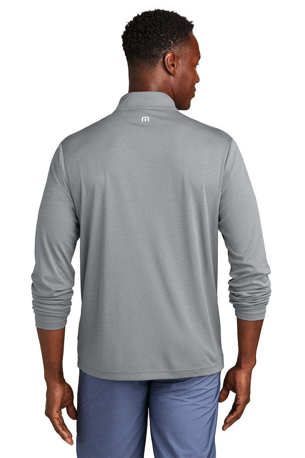 Man wearing a gray long-sleeve shirt with a logo on the back, standing against a white background. embroidered TravisMathew Coto Performance 1/4-Zip