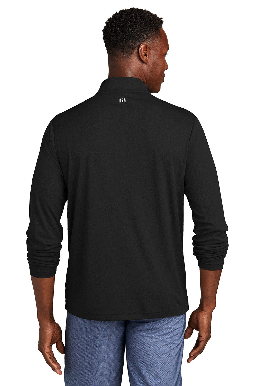 Man wearing a black long-sleeve shirt with a logo on the back, standing against a white background. embroidered TravisMathew Coto Performance 1/4-Zip