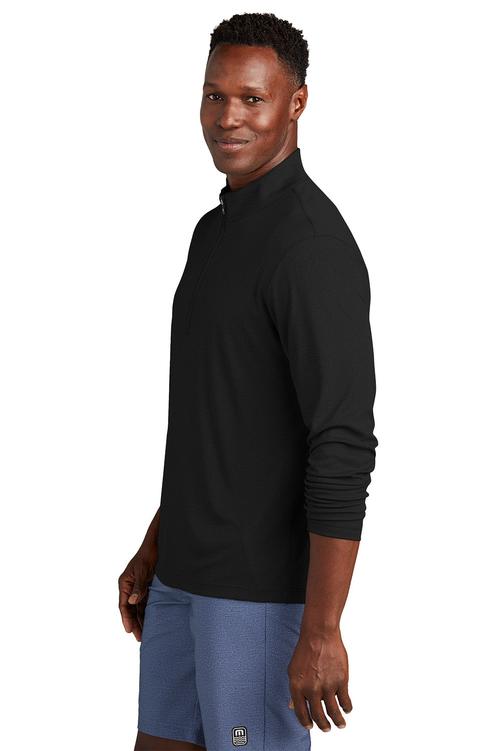Man wearing a black long-sleeve shirt and blue shorts on a white background, embroidered TravisMathew Coto Performance 1/4-Zip