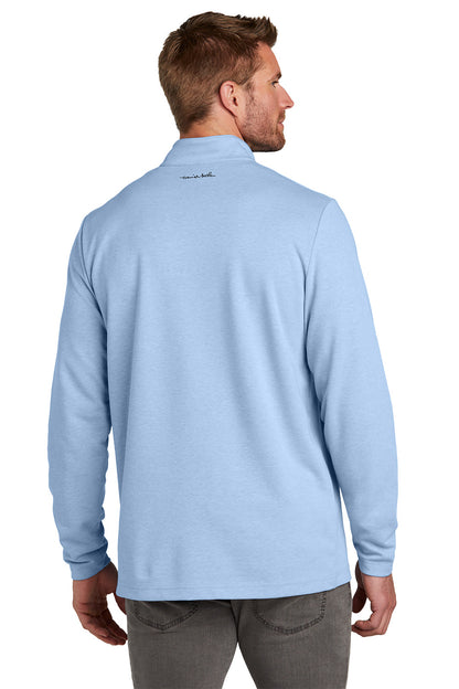 Man wearing a light blue long-sleeve shirt with a logo on the chest against a white background TravisMathew Coveside 1/4-Zip, Embroidered