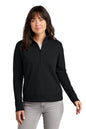 Woman wearing a black long-sleeve shirt with a quarter zip on a white. TravisMathew Women's Ocean Villa 1/4-Zip, Embroidered background