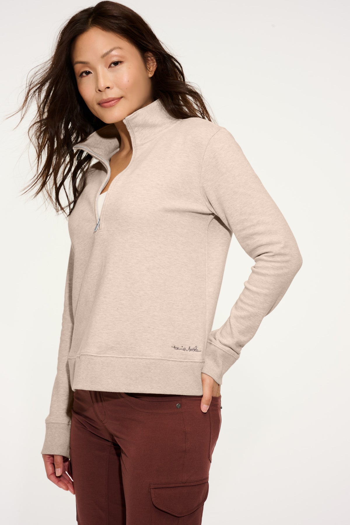 Woman wearing a beige fleece jacket and brown pants on a white background. TravisMathew Women's Ocean Villa 1/4-Zip, Embroidered