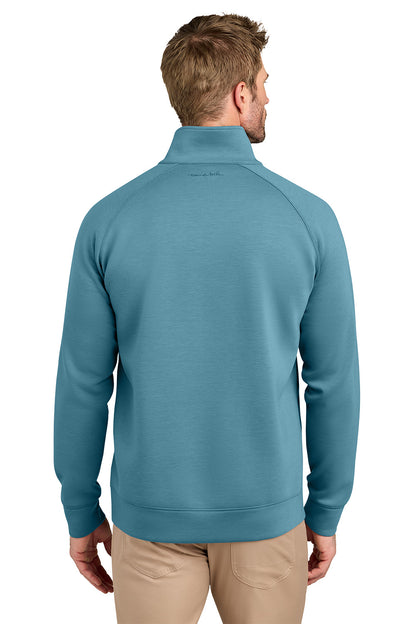 A man viewed from the back wearing a teal blue quarter-zip pullover sweatshirt and khaki pants, set against a plain white background. TravisMathew Momentum Shift 1/4-Zip, Embroidered