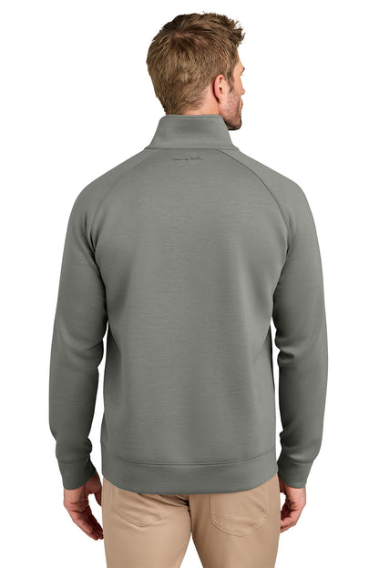 A man viewed from the back wearing a sage green quarter-zip pullover sweatshirt and khaki pants, set against a plain white background. TravisMathew Momentum Shift 1/4-Zip, Embroidered