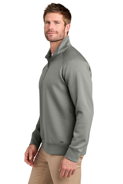 A man wearing a gray quarter-zip pullover sweater and khaki pants, shown from a side profile against a white background. TravisMathew Momentum Shift 1/4-Zip, Embroidered