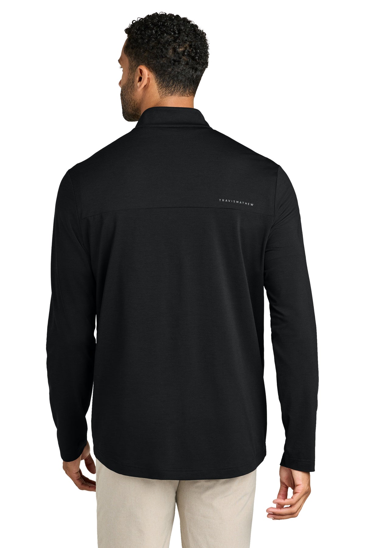 Person wearing a black long-sleeve shirt with a brand logo on the back, standing against a white background. TravisMathew Onward 1/2-Zip, Embroidered