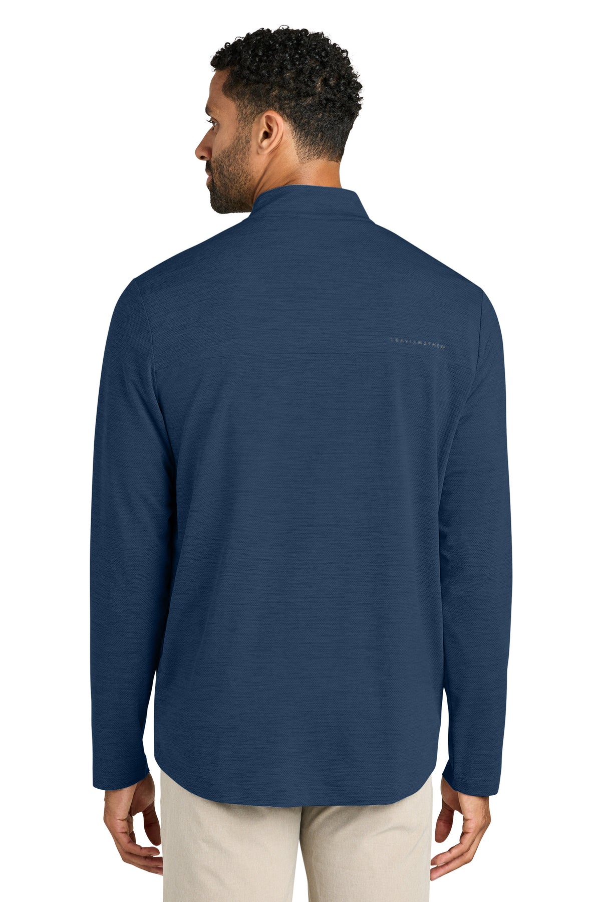 Man wearing a blue long-sleeve shirt with a brand logo on the back, standing against a white background. TravisMathew Onward 1/2-Zip, Embroidered