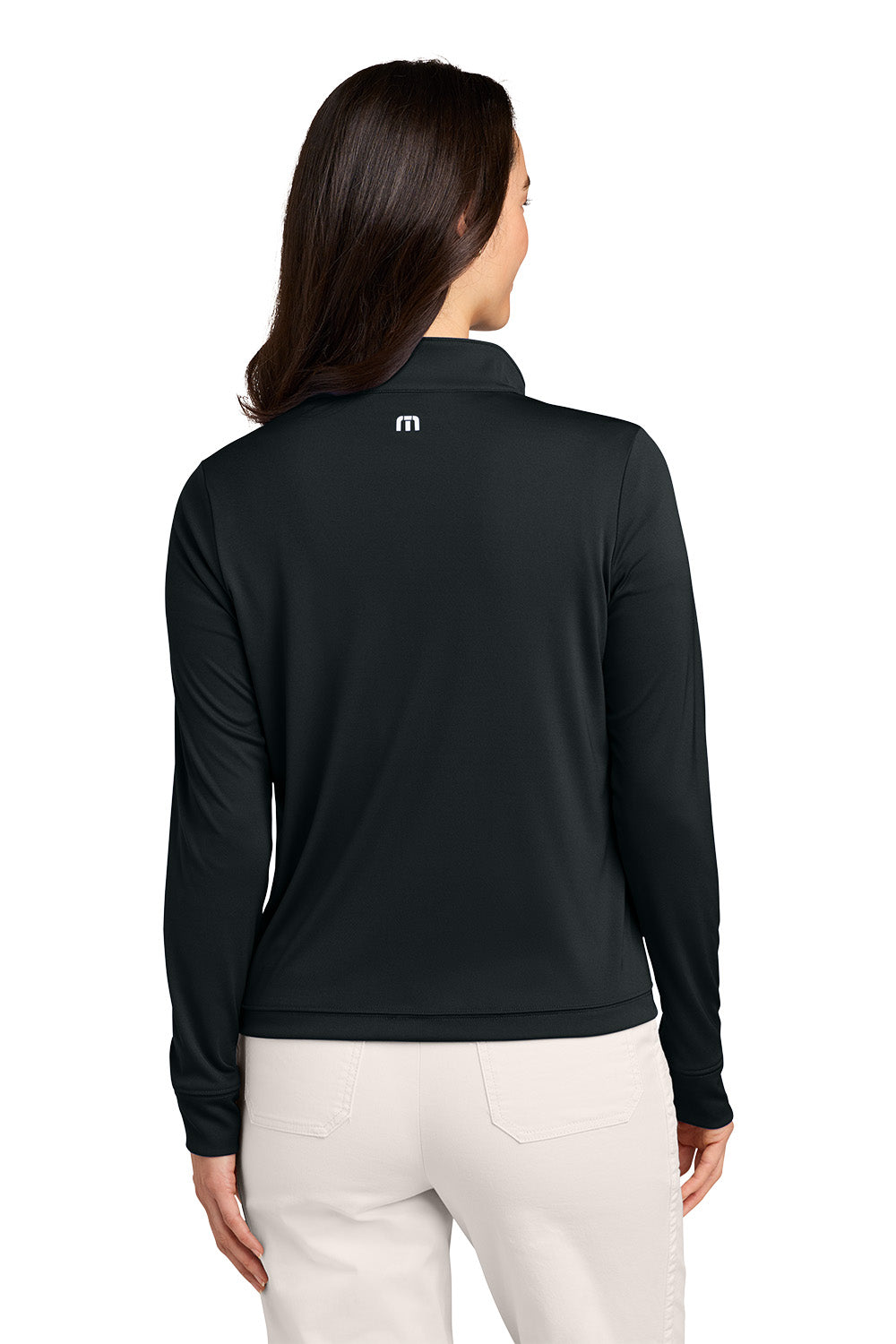 A woman viewed from the back wearing a black long-sleeve quarter-zip pullover with a small white logo on the upper back, paired with off-white pants, against a plain white background. TravisMathew Women's Coto Performance 1/2-Zip, Embroidered