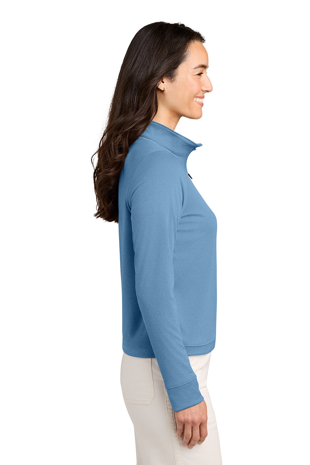 A woman shown in side profile wearing a light blue long-sleeve quarter-zip pullover and off-white pants, photographed against a plain white studio background. TravisMathew Women's Coto Performance 1/2-Zip, Embroidered