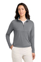 A woman modeling a gray long-sleeve quarter-zip pullover with a stand collar, paired with off-white pants, against a plain white background. TravisMathew Women's Coto Performance 1/2-Zip, Embroidered