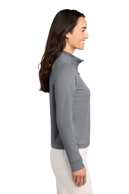 A woman shown in side profile wearing a gray long-sleeve quarter-zip pullover and off-white pants, photographed against a plain white studio background. TravisMathew Women's Coto Performance 1/2-Zip, Embroidered