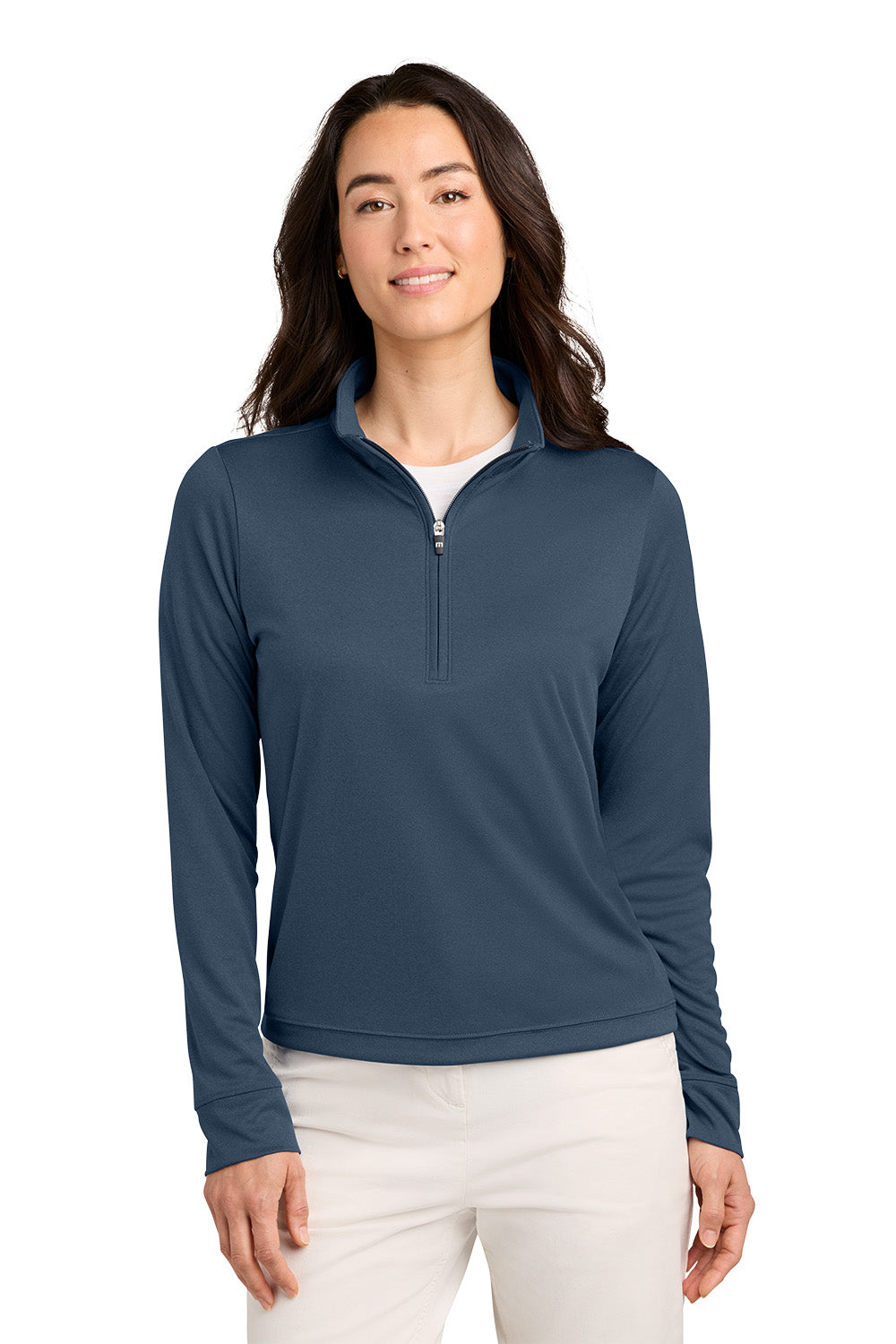 A woman modeling a slate blue quarter-zip long-sleeve performance pullover, paired with white pants, against a solid white background. TravisMathew Women's Coto Performance 1/2-Zip, Embroidered