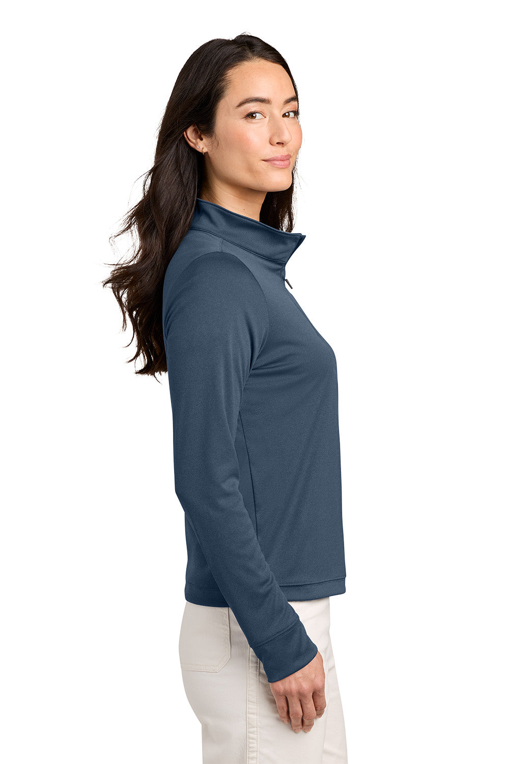 A woman shown in side profile wearing a slate blue long-sleeve quarter-zip pullover and white pants, photographed against a solid white background. TravisMathew Women's Coto Performance 1/2-Zip, Embroidered