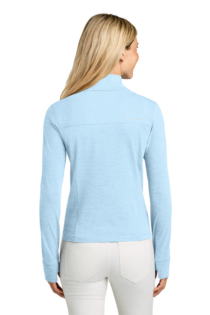 Woman wearing a light blue long-sleeve top on a white background. TravisMathew Women’s Onward 1/2-Zip, Embroidered