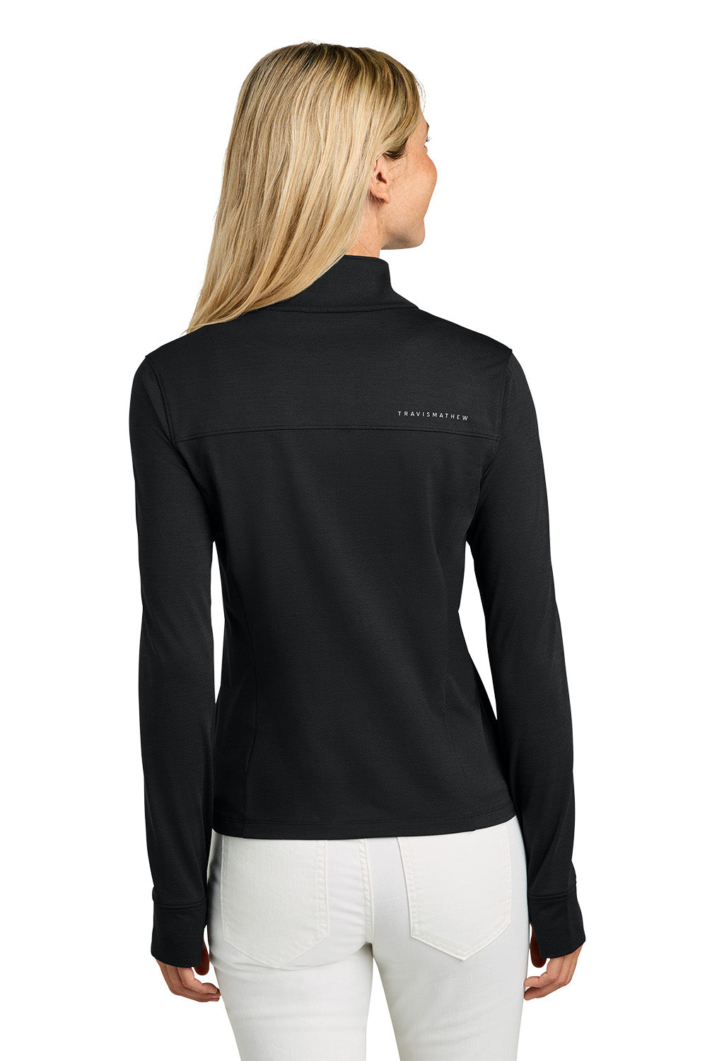 Woman wearing a black long-sleeve shirt with a visible brand logo on the back, standing against a white background. TravisMathew Women’s Onward 1/2-Zip, Embroidered