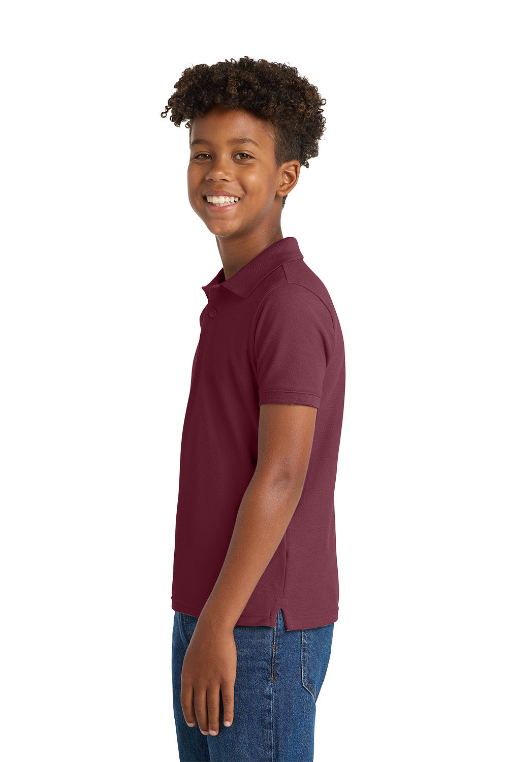 Young boy wearing a maroon polo shirt and blue jeans on a white background. Port Authority® Youth Core Classic Pique Polo, Embroidered by Helmsman Stitch Co.