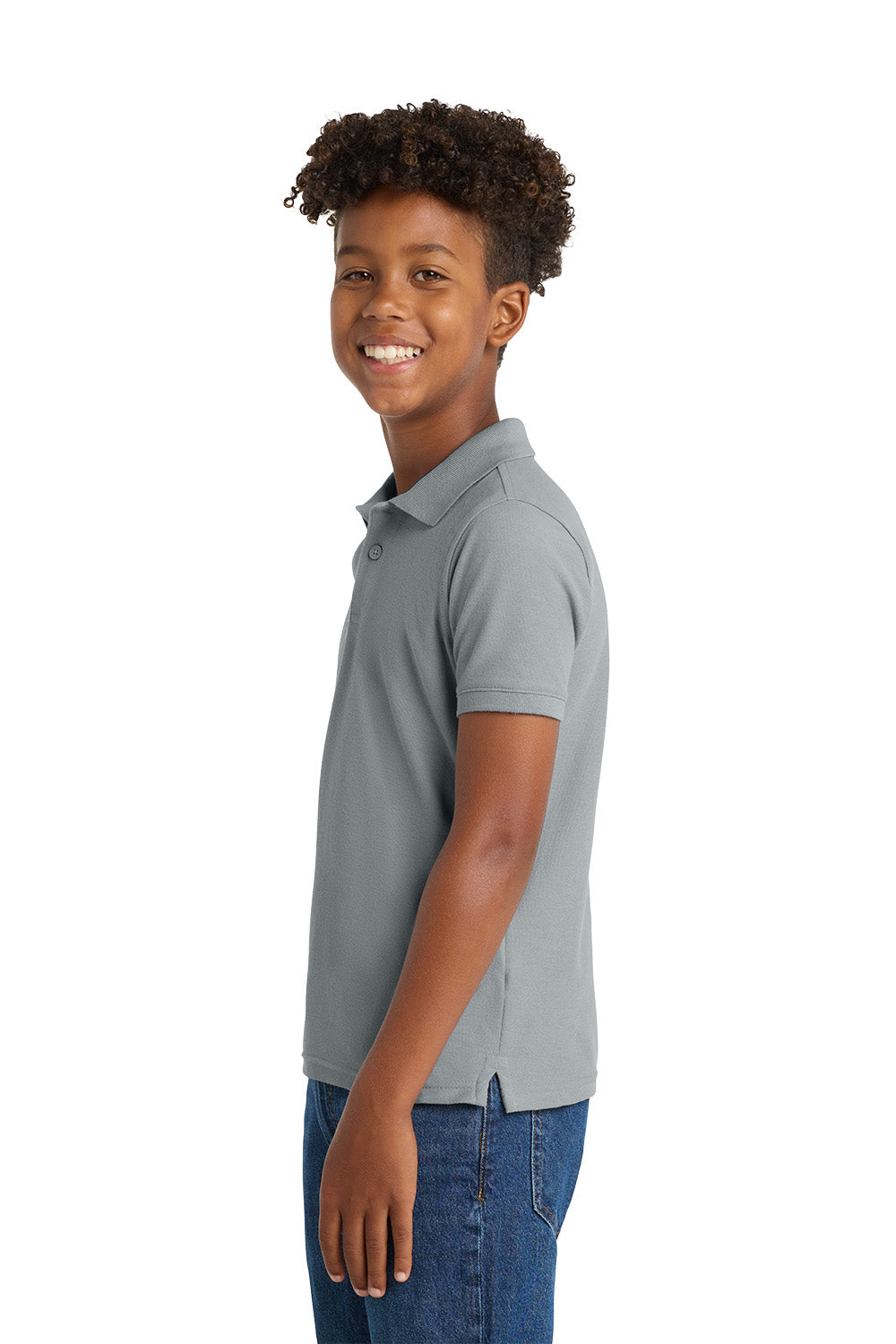 Young boy wearing a gray polo shirt and blue jeans on a white background. Port Authority® Youth Core Classic Pique Polo, Embroidered by Helmsman Stitch Co.