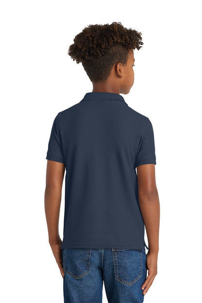 Person wearing a navy blue polo shirt and jeans on a white background. Port Authority® Youth Core Classic Pique Polo, Embroidered by Helmsman Stitch Co.